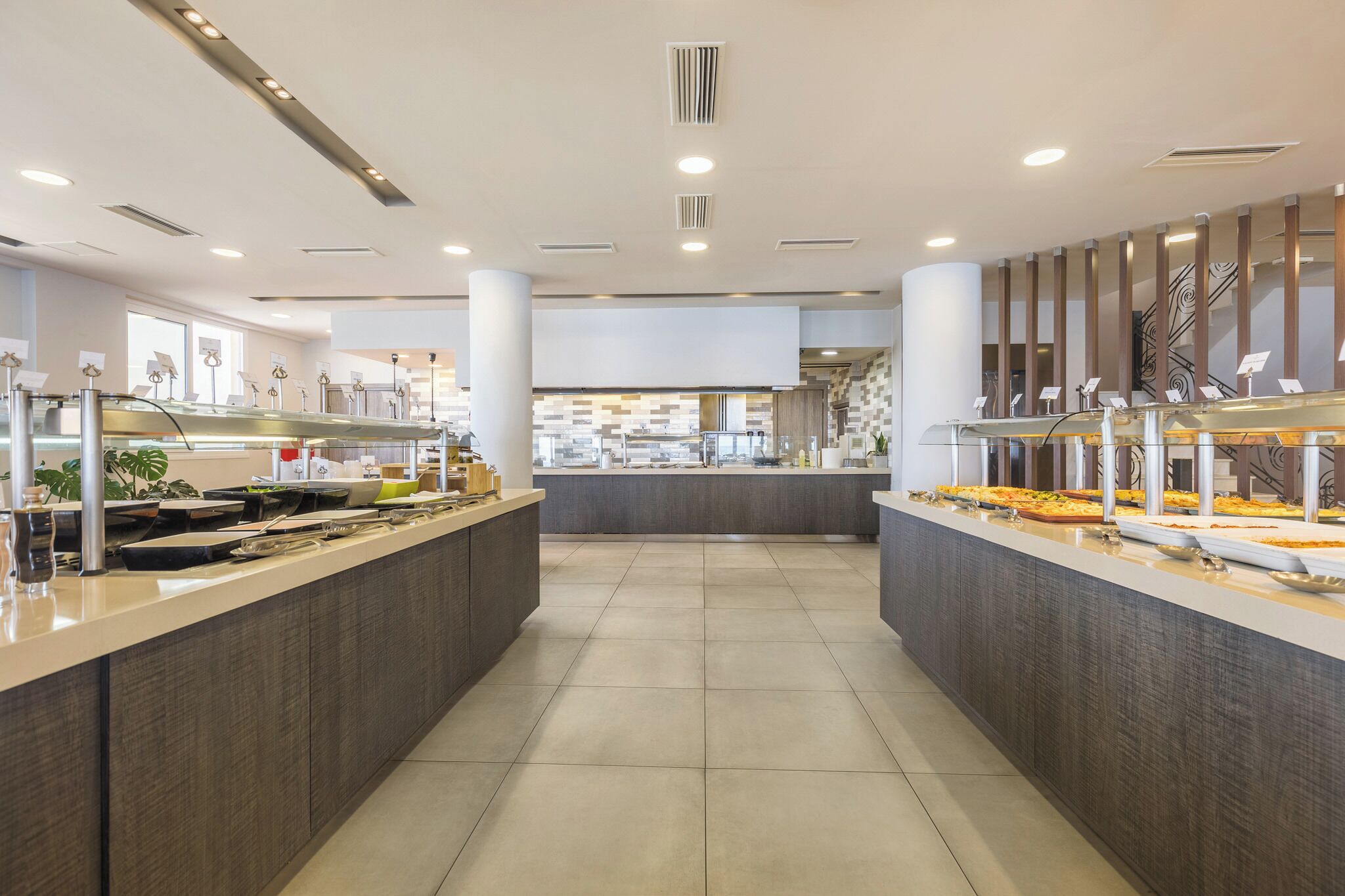 Un moderno bufé con una estación central de servicio y dos áreas de exhibición de alimentos.