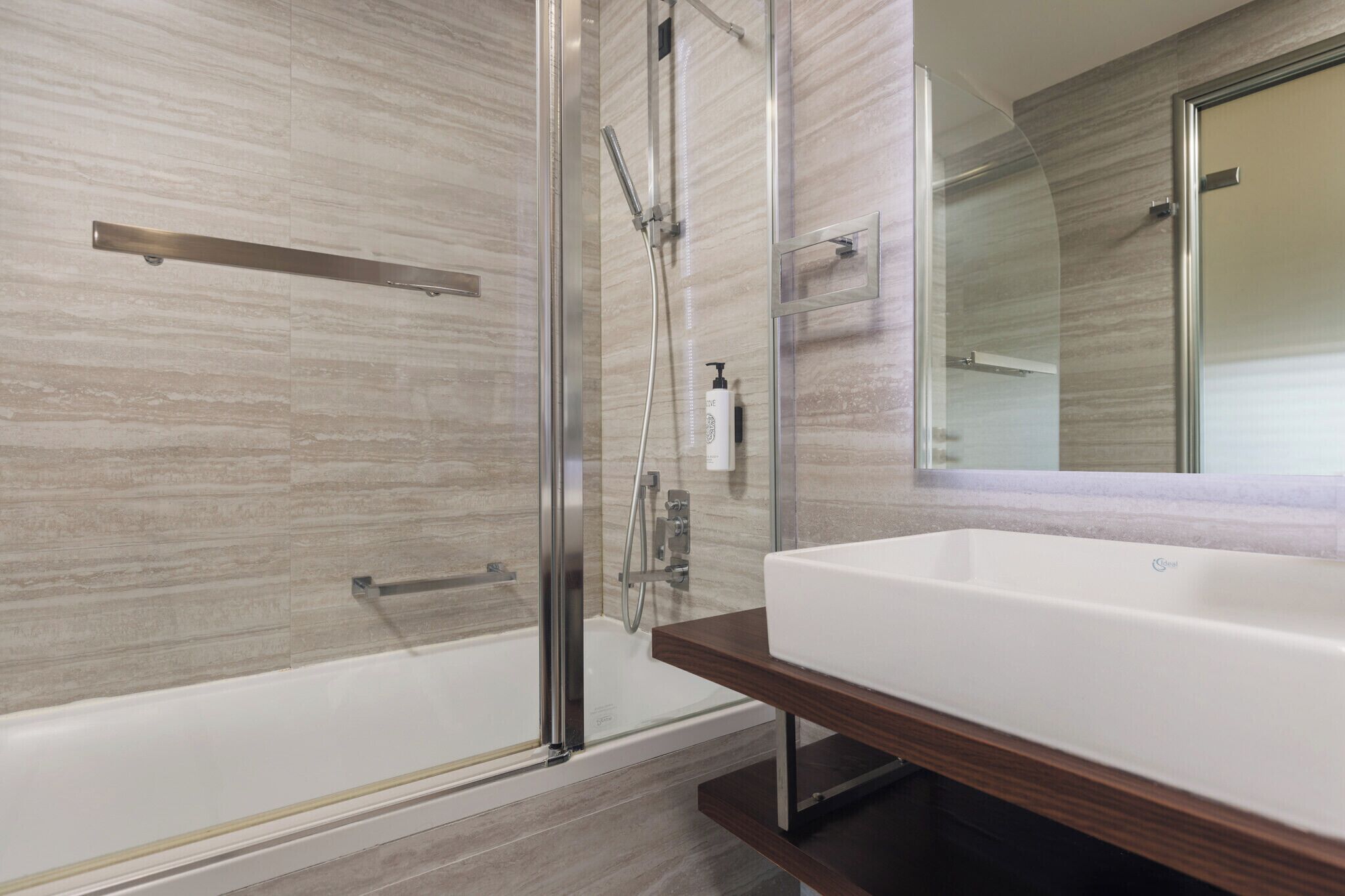 Un bagno moderno con doccia a vetro, vasca da bagno bianca e un grande specchio sopra il lavandino.