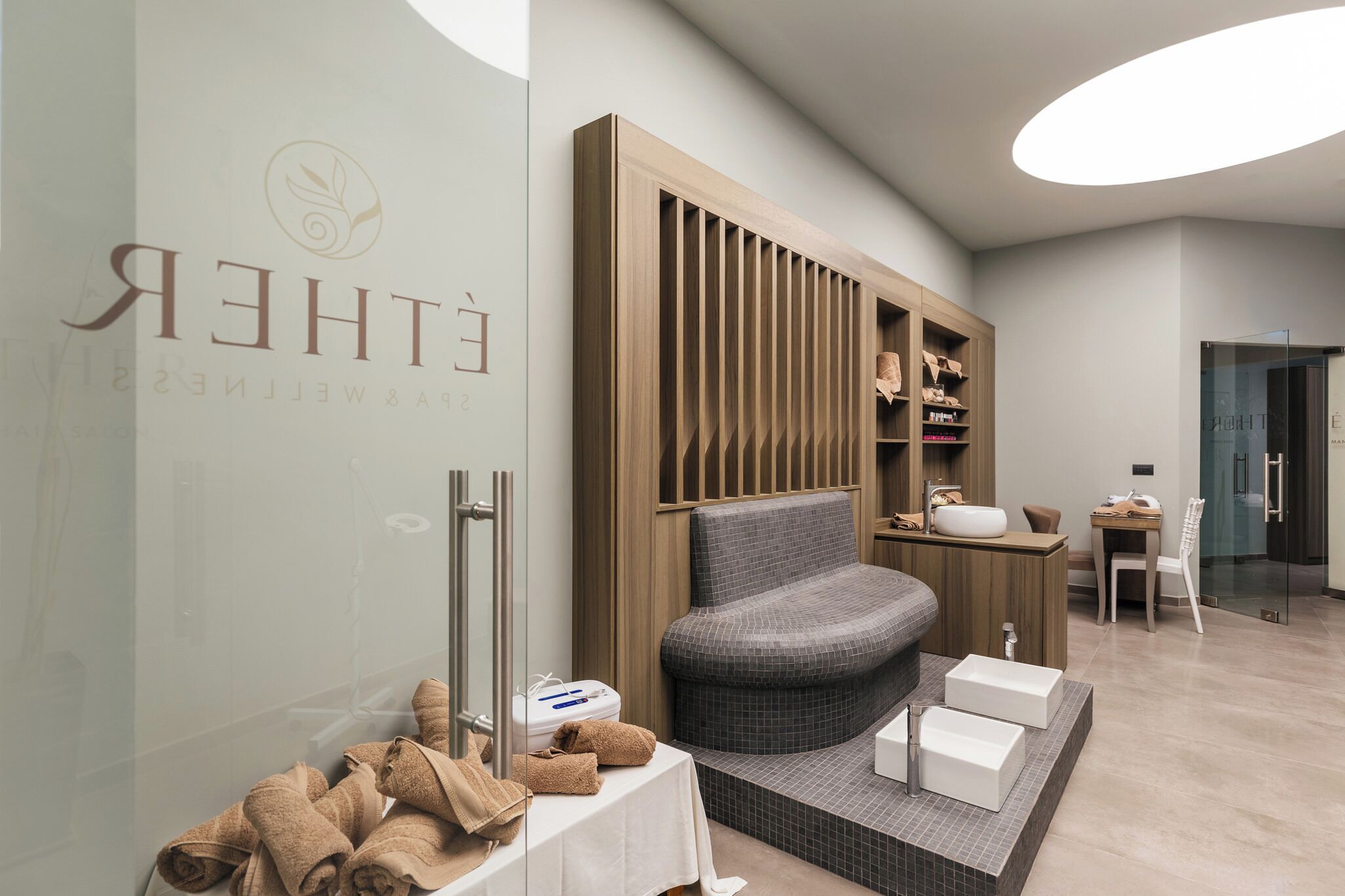 A modern spa room with a curved seating area, a wooden panel wall, and a glass shower enclosure.