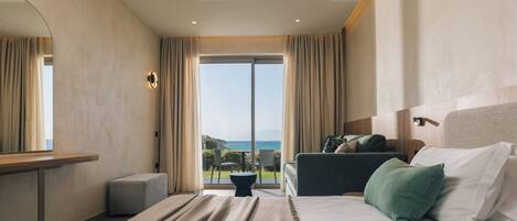 A hotel room with a bed, a desk, a chair, and a view of the sea.