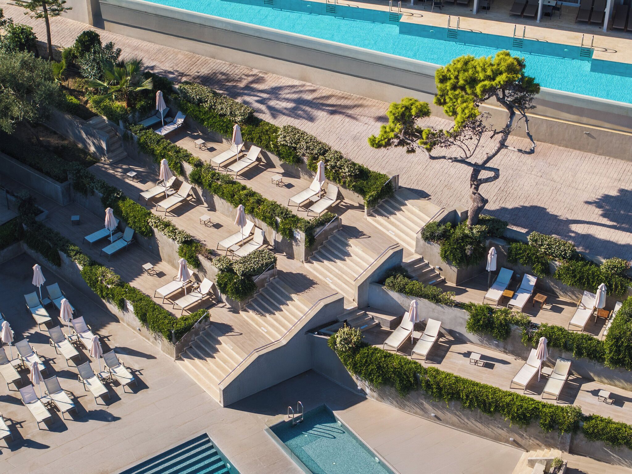 Vue aérienne d’un complexe hôtelier doté de plusieurs piscines, de chaises longues et d’un jardin bien entretenu.