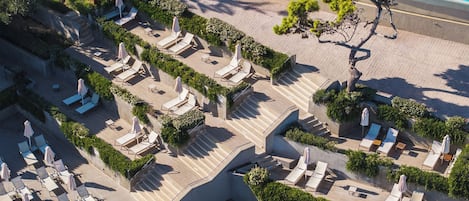 Vista aérea de un resort con varias piscinas, tumbonas y un jardín bien cuidado.