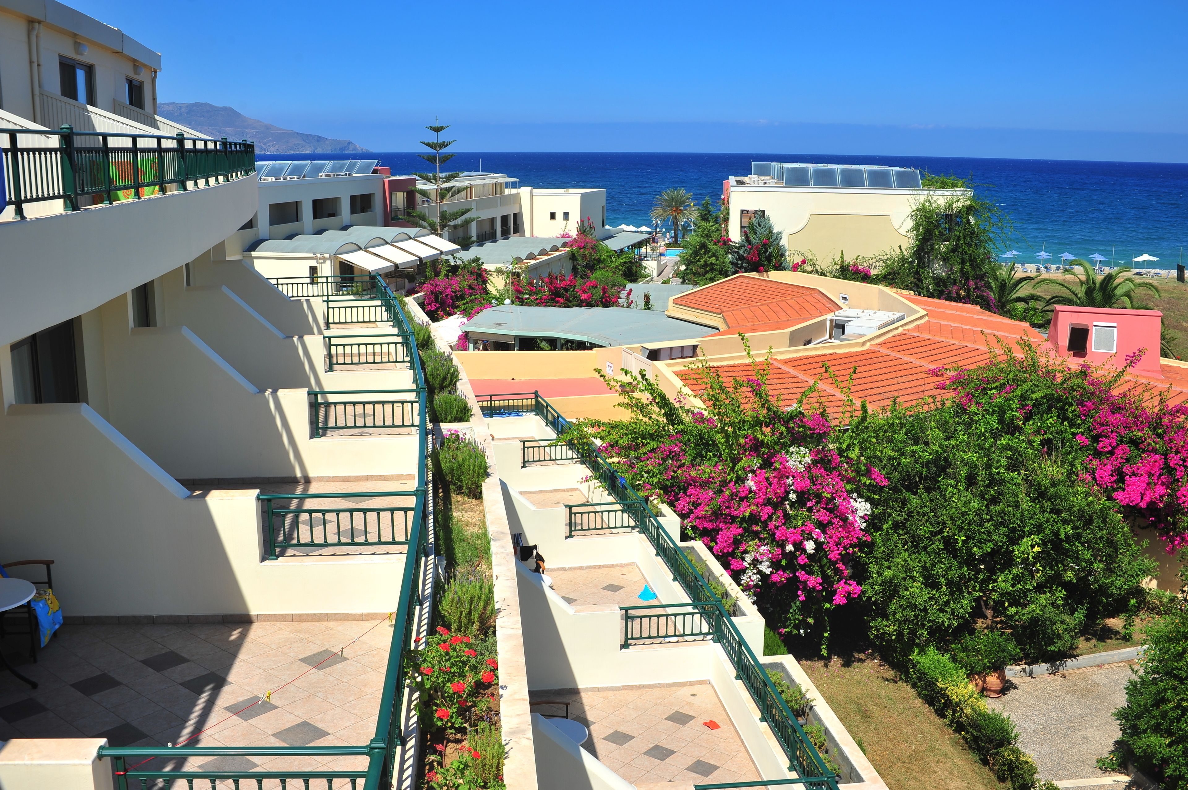 Un hotel con varios balcones, mobiliario exterior y vista al mar.
