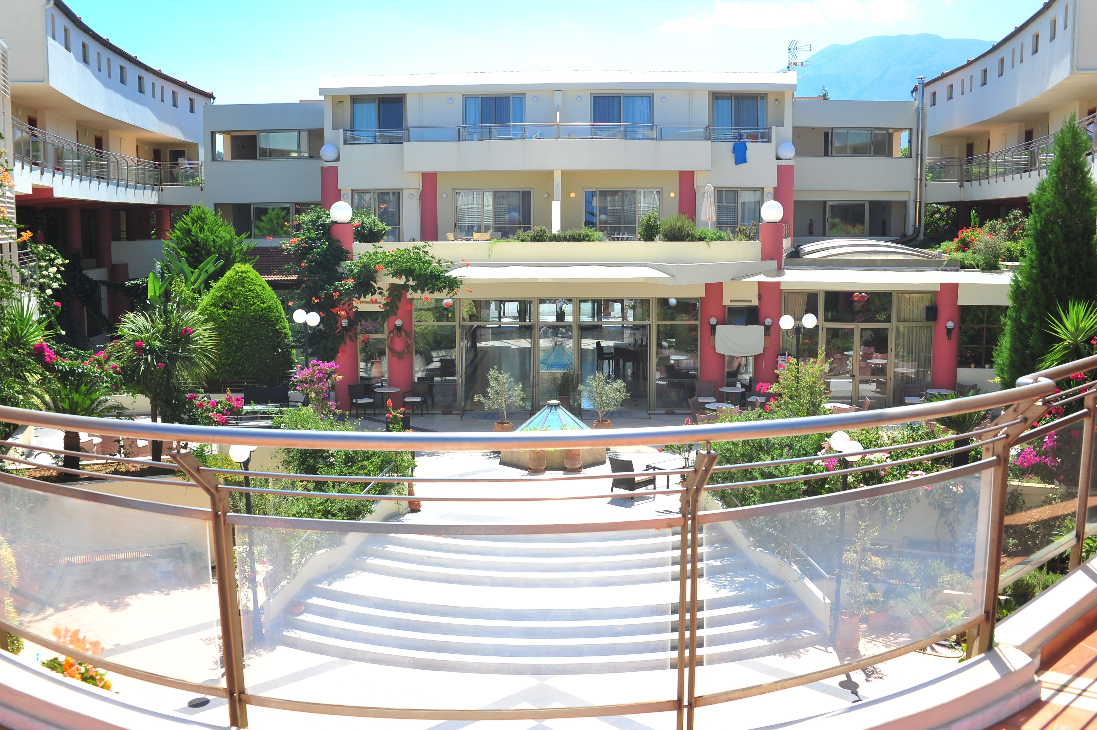 Un hôtel à plusieurs étages doté d’une cour intérieure aménagée avec des espaces de détente en plein air, une piscine et une végétation luxuriante.