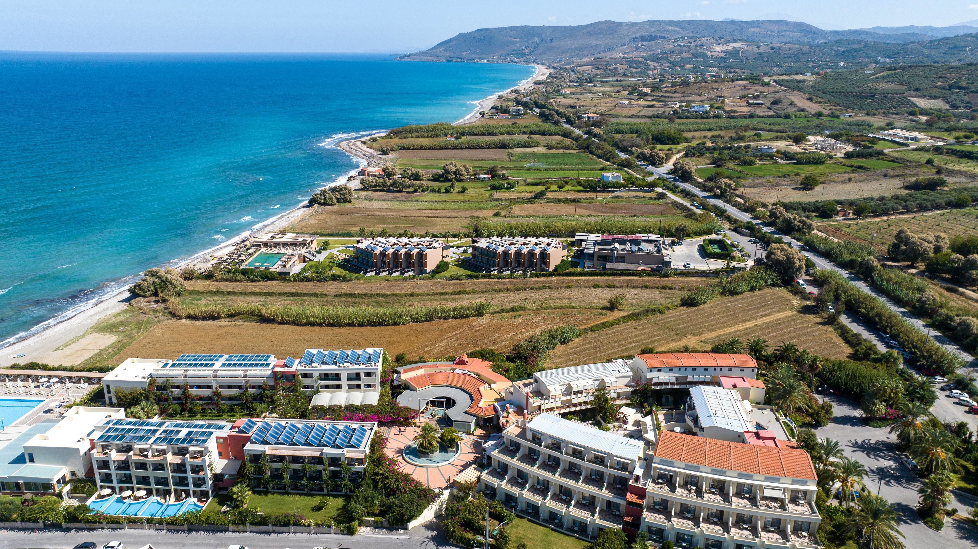 A coastal resort with multiple buildings, a swimming pool, and solar panels.