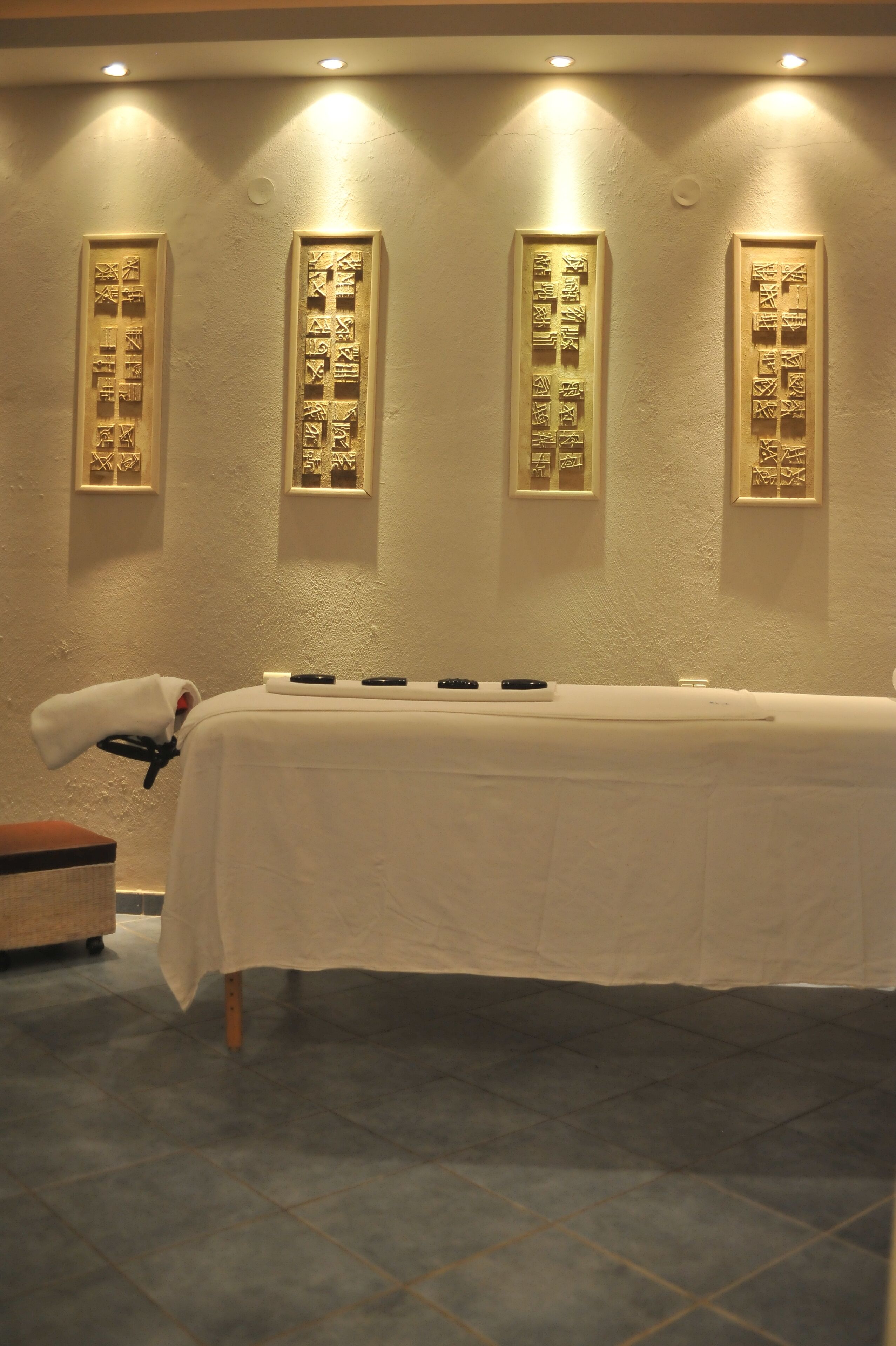 A room with a massage table, a towel, and framed artwork on the wall.