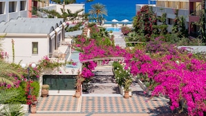 A coastal hotel with a checkered courtyard, a tall pine tree, and a view of the sea. - Hydramis Palace Beach Resort (Apokoronas)