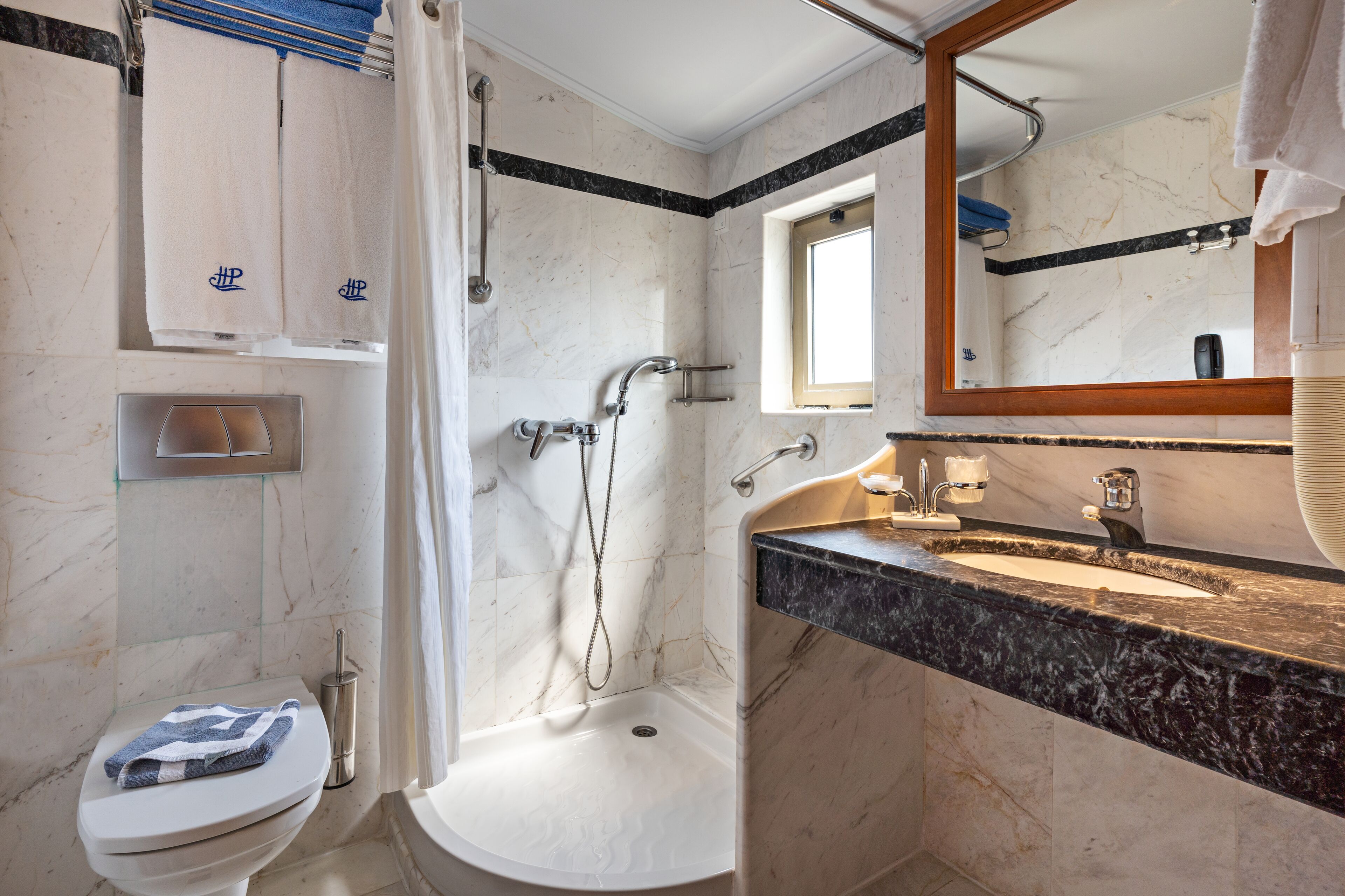 A bathroom with a shower, toilet, sink, and a large mirror.
