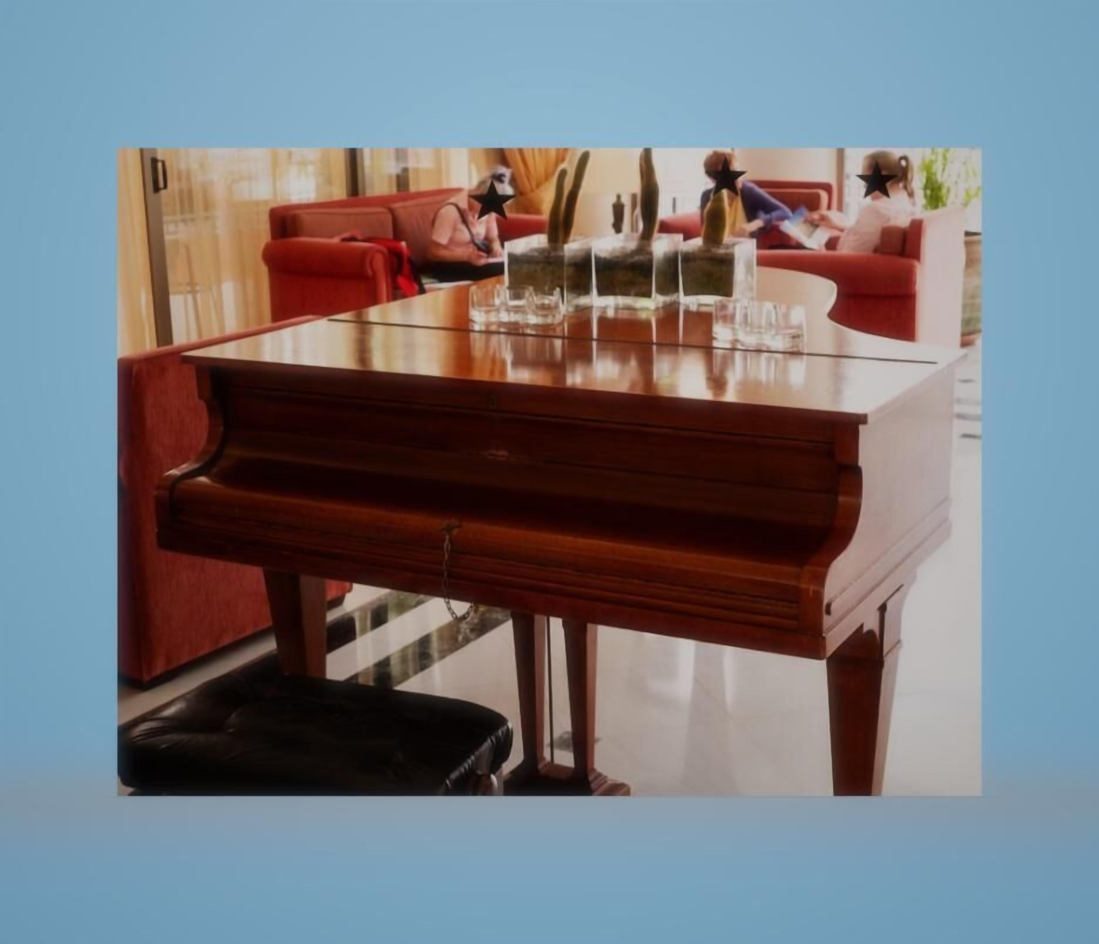 Un piano de cola en una habitación bien iluminada, con un sofá rojo y una mesa de vidrio.