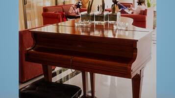Un piano de cola en una habitación bien iluminada, con un sofá rojo y una mesa de vidrio.
