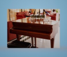 Un piano de cola en una habitación bien iluminada, con un sofá rojo y una mesa de vidrio.