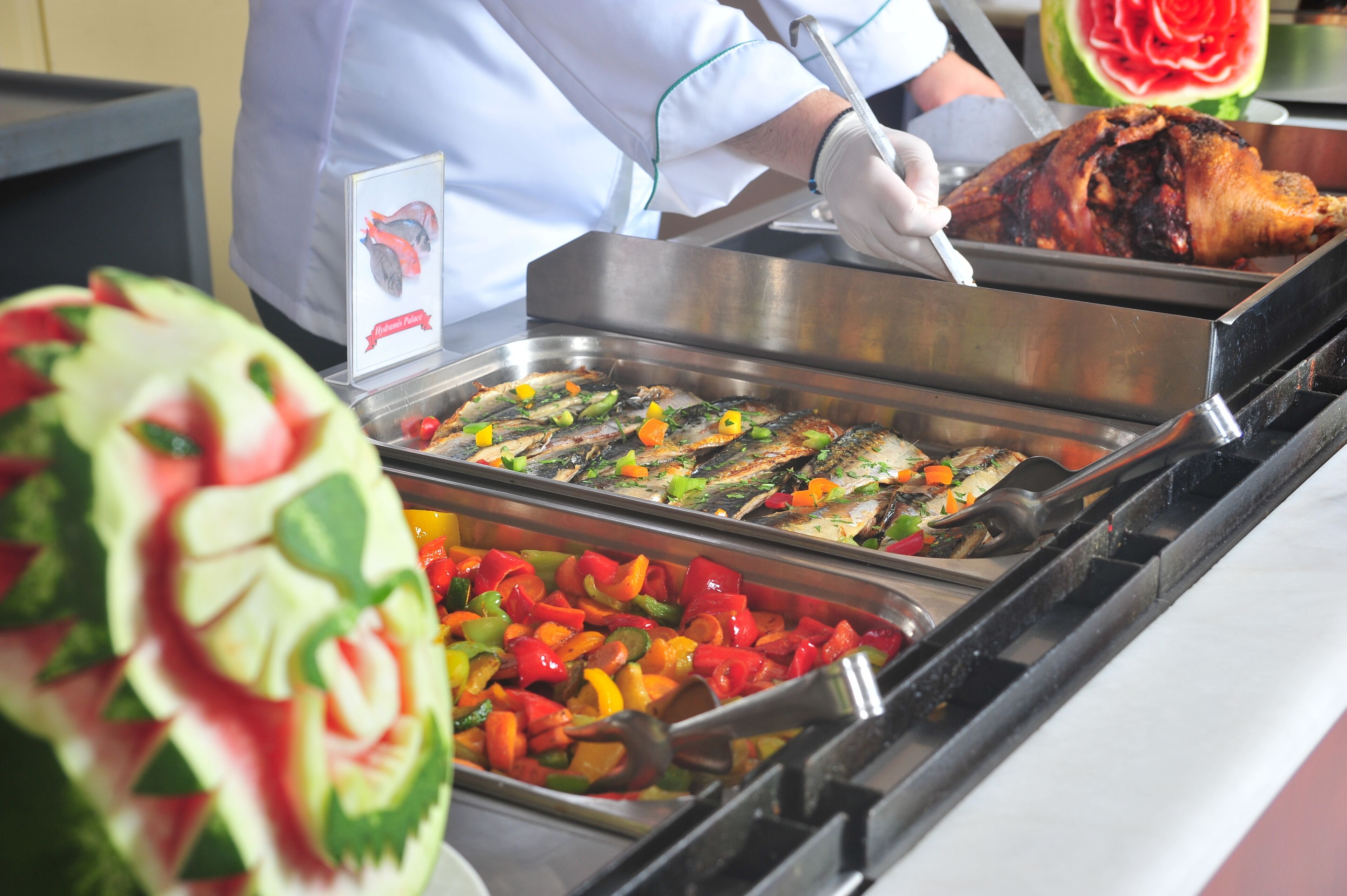 A buffet with various dishes, including grilled fish and colorful vegetables.