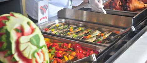 A buffet with various dishes, including grilled fish and colorful vegetables.