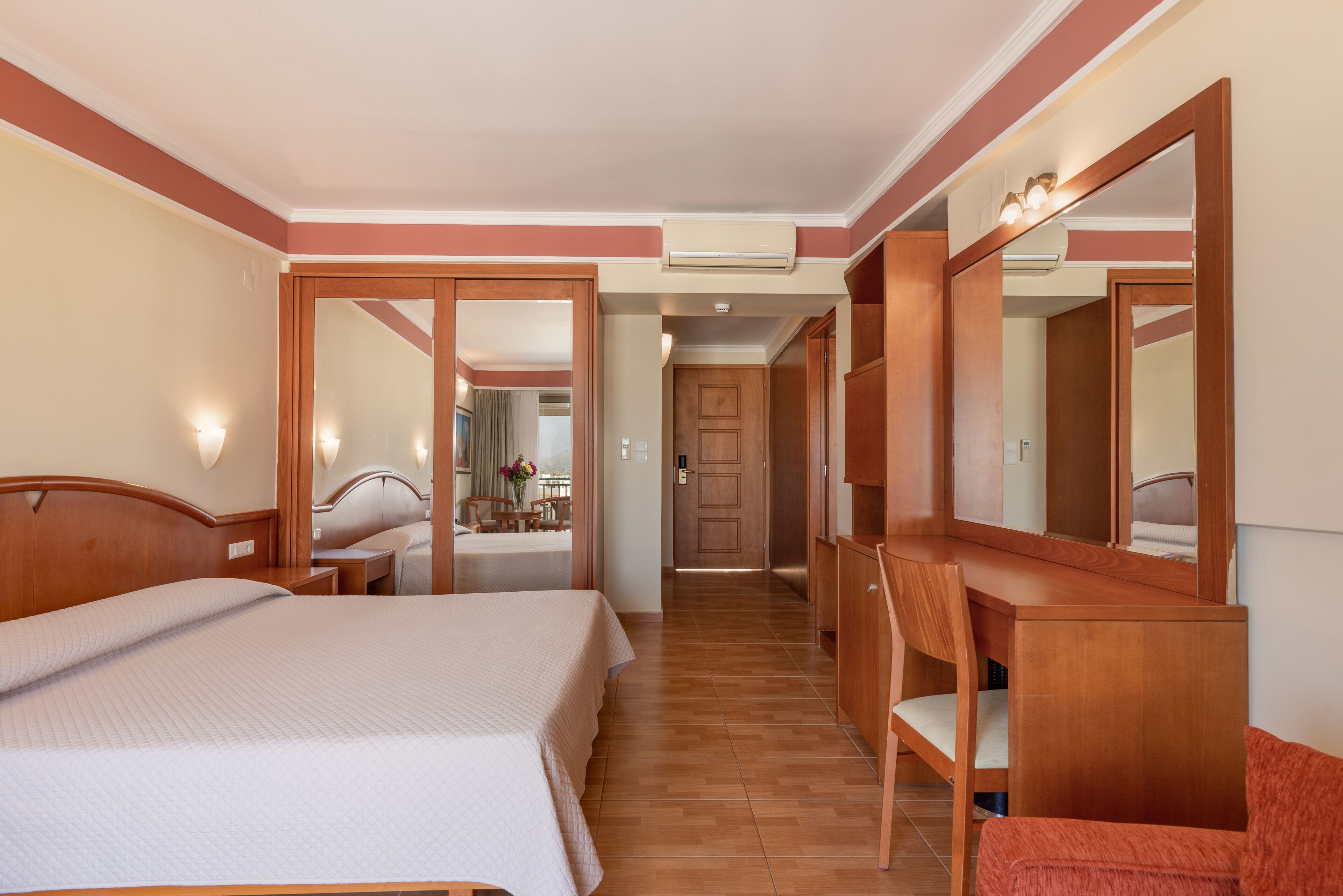 Een hotelkamer met een bed, een bureau, een stoel en een grote spiegel.
