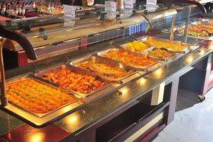 A buffet with various food options including salads, meats, and desserts.