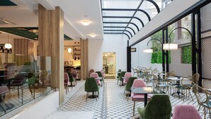 A modern cafe with a geometric tiled floor, wooden accents, and a variety of seating options including chairs and tables. - Jo An Palace Hotel (Rethymno)
