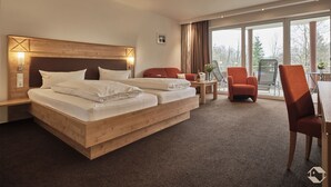 Hotellihuone, jossa on suuri sänky, työpöytä tuolilla sekä parveke, jolta on näkymä.
