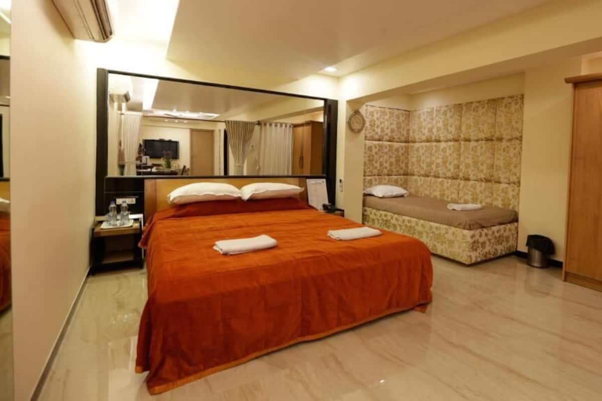 A hotel room with a large bed, a smaller bed, a wardrobe, and a mirror.