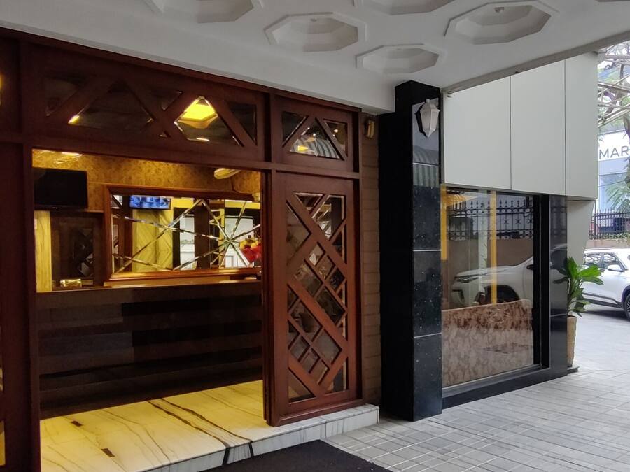 A building facade with a wooden lattice design, a visible entrance, and parked cars outside.