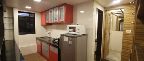 A compact kitchen with a refrigerator, microwave, and stove.