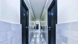 A modern hotel corridor with marble flooring, black doors, and a long hallway. - Hotel Metro Palace (Mumbai)