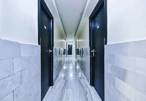 Un pasillo moderno de hotel con suelo de mármol, puertas negras y una larga galería.