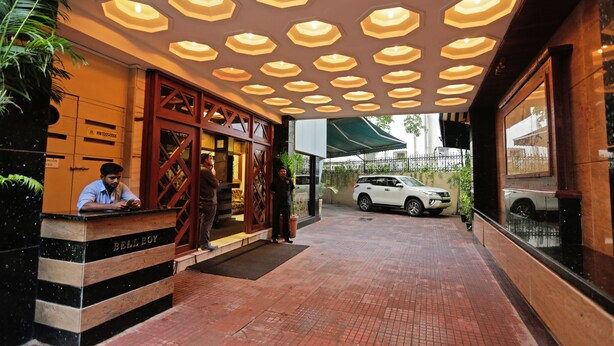 A hotel entrance with a reception desk, a car parked outside, and a distinctive ceiling design. - Hotel Metro Palace (Mumbai)