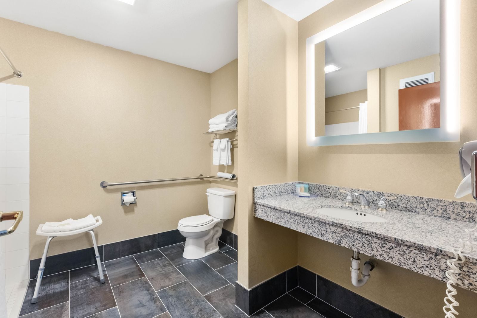 Une salle de bain équipée de toilettes, d’un sèche-mains et d’un lavabo doté d’un plan de travail en granit.