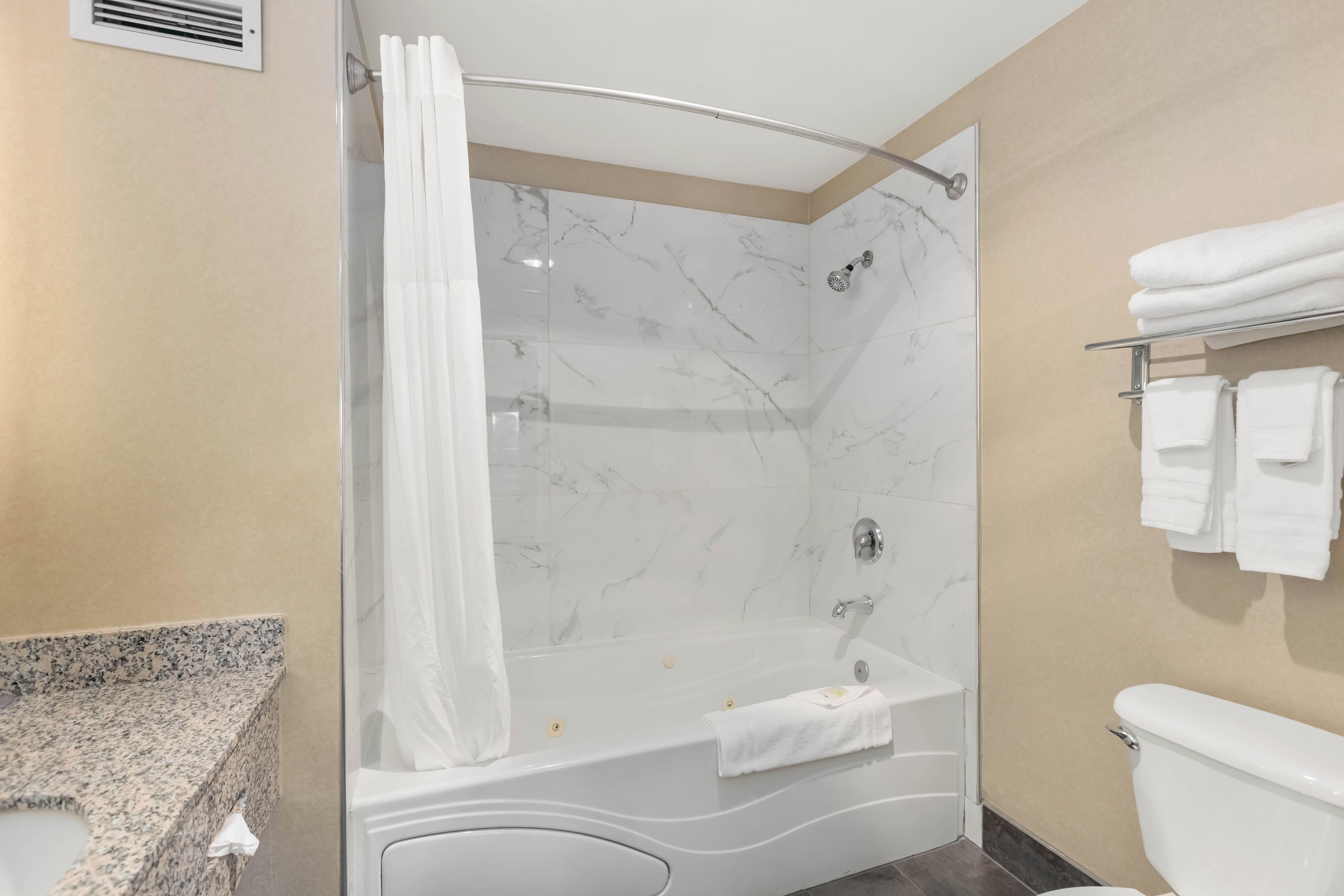 A modern bathroom with a glass shower enclosure, a white bathtub, and a toilet.