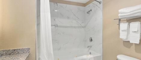 A modern bathroom with a glass shower enclosure, a white bathtub, and a toilet.
