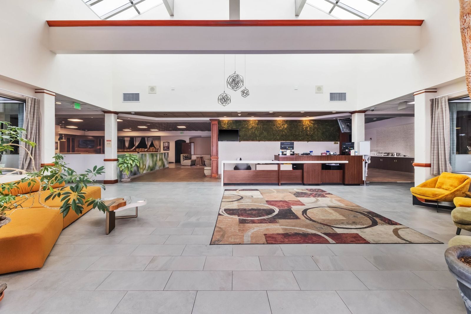 A spacious lobby with a reception desk, seating area, and a view of the kitchen in the background.