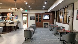 A restaurant with a bar area, multiple tables, and a fireplace.