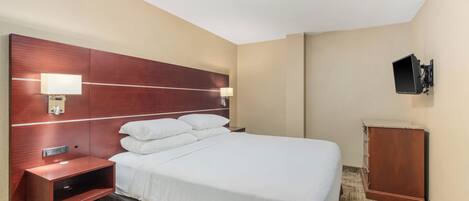 Une chambre d’hôtel avec un lit, des lampes de chevet, un téléviseur fixé au mur et une petite armoire en bois.