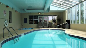 An indoor swimming pool with clear blue water, a lifeguard chair, and a sign indicating a 3 ft depth.
