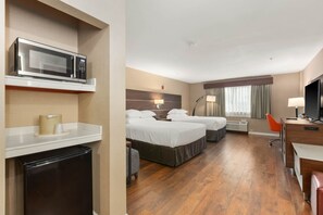 A hotel room with two beds, a desk, a television, a microwave, and a mini-fridge. - Medallion Inn & Suites (Arlington)