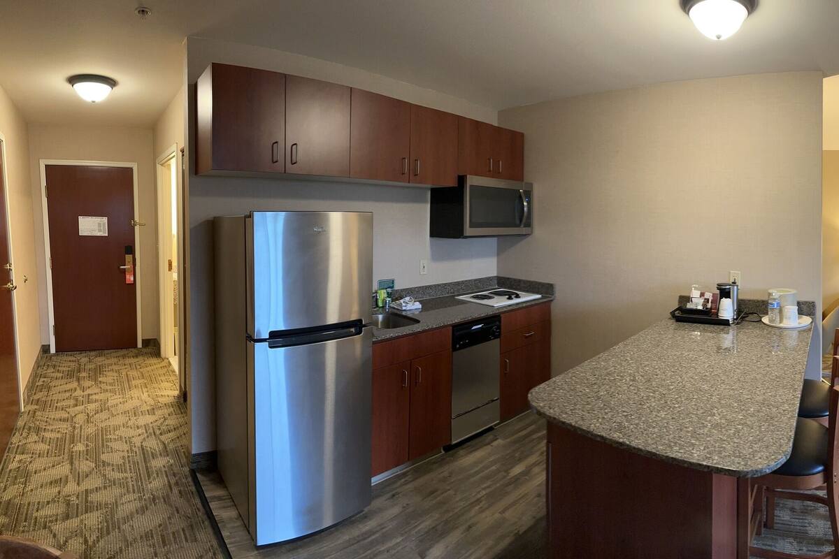 Habitación de hotel con kitchenette, cama, televisor y ventana con vistas.