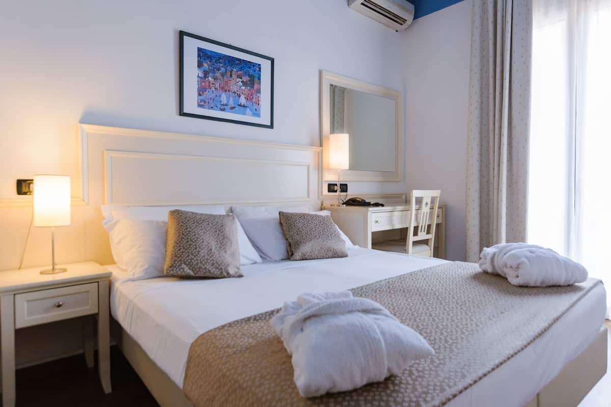 A neatly made bed with pillows, a bedside lamp, and a framed picture on the wall.