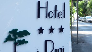 Skilt for Hotel Tra i Pini med et træ og tre stjerner.