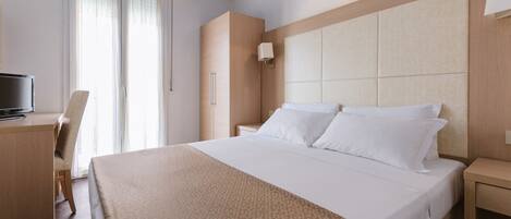 A hotel room with a large bed, a desk, and a chair.
