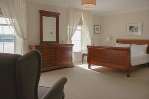 A bedroom with a wooden bed, a dresser, a chair, and a large mirror.