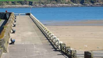A stone pathway leading to a beach with benches and a flag.
