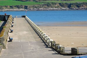 A stone pathway leading to a beach with benches and a flag.