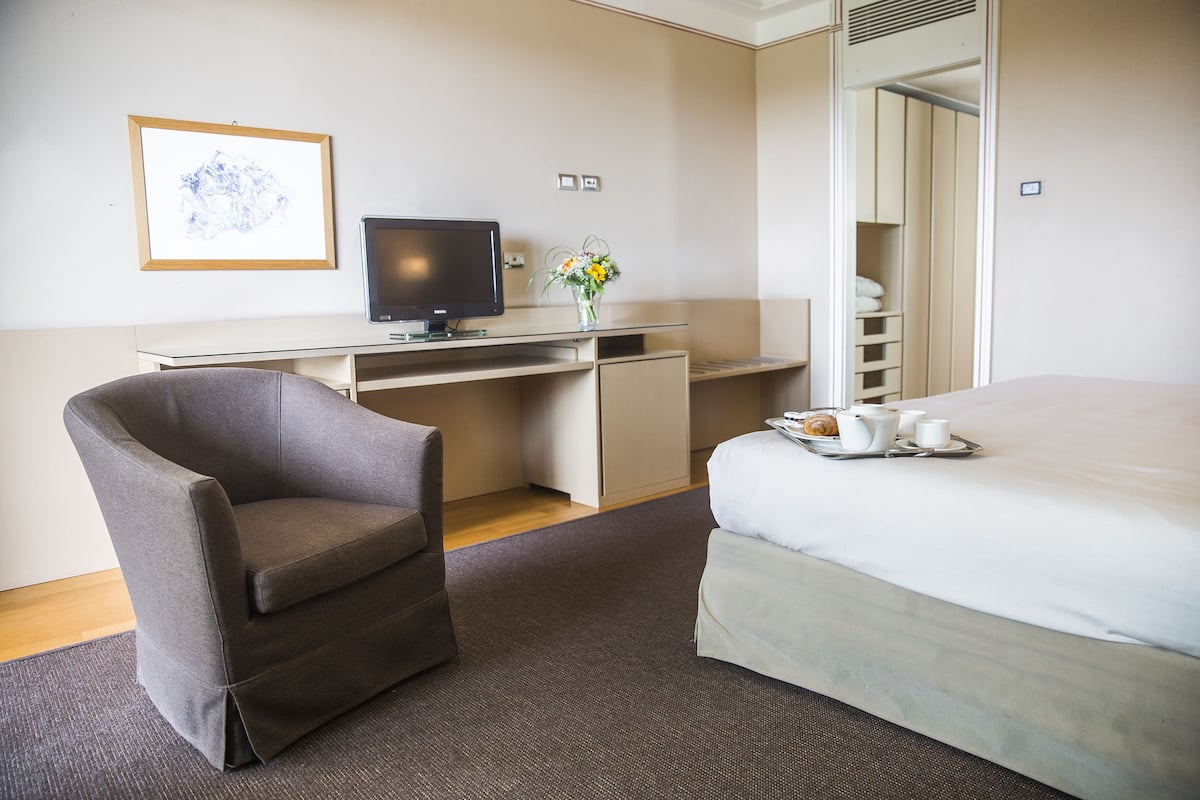 Habitación de hotel con cama, escritorio con computadora, silla y bandeja con alimentos para el desayuno.