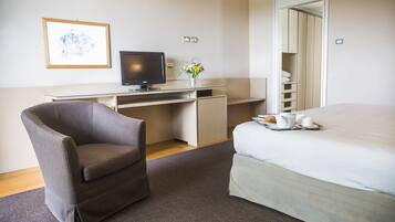 Habitación de hotel con cama, escritorio con computadora, silla y bandeja con alimentos para el desayuno.