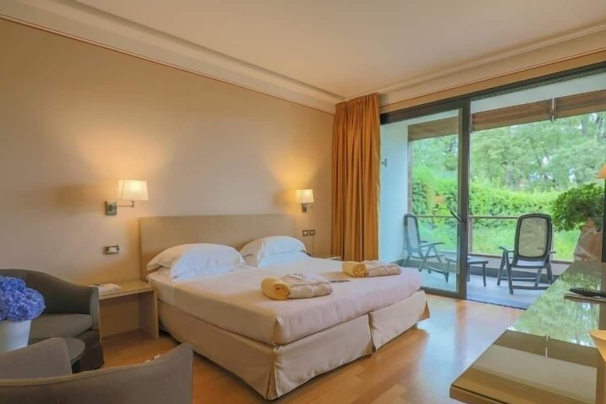 Habitación de hotel con una cama grande, un escritorio, una silla y vistas al exterior.