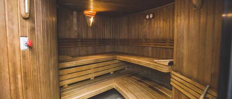A sauna with wooden benches and a sloped floor.