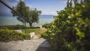 A stone staircase leading to a grassy area with a view of a calm body of water and distant land. - Hotel Acquaviva del Garda (Desenzano del Garda)