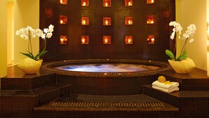 A spa area with a hot tub, tiled walls, and potted orchids. - Grecotel Meli Palace (Agios Nikolaos)