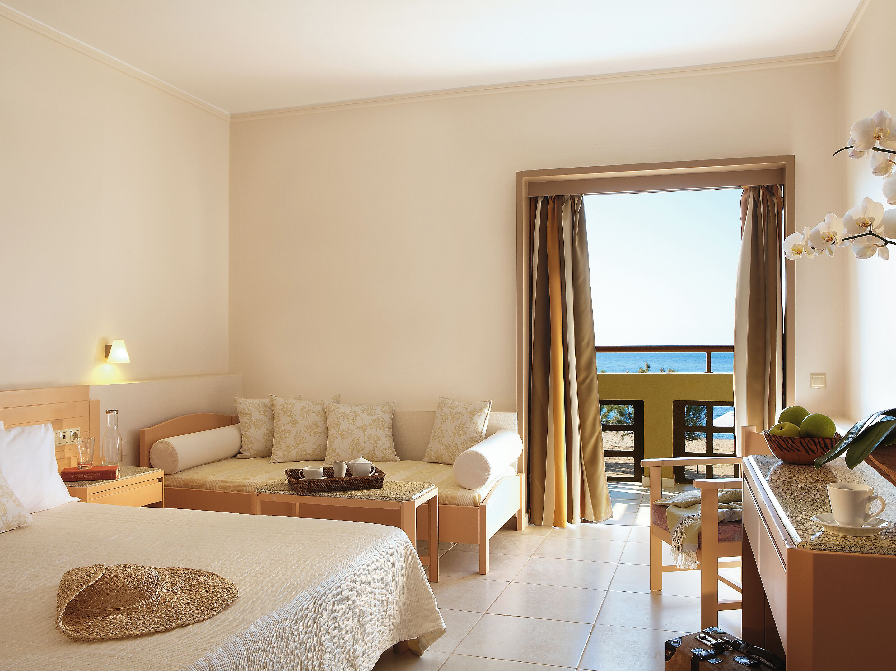Une chambre d’hôtel avec un lit, un canapé, une table à manger et une vue sur la mer.