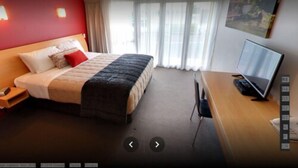 A hotel room with a bed, a desk with a computer, and a window with curtains. - Park View Motor Lodge (Hamilton)